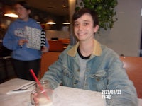 a young man sitting at a table with a cup of milk