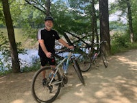 a man standing next to his bike next to a river