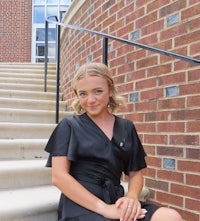 a young woman sitting on steps in a black dress